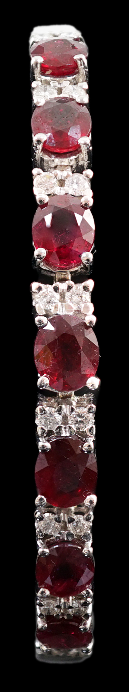 A 750 white gold and seven stone oval cut ruby set line bracelet, set with sixteen stone diamond spacers